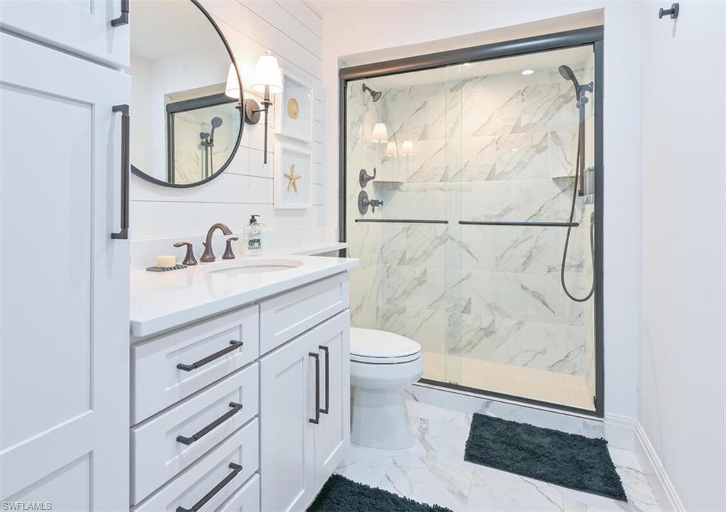 3105 Riviera Drive, Unit A201 Naples, FL 34103 - Photo 24 of 30 a bathroom with a sink a toilet and a mirror
