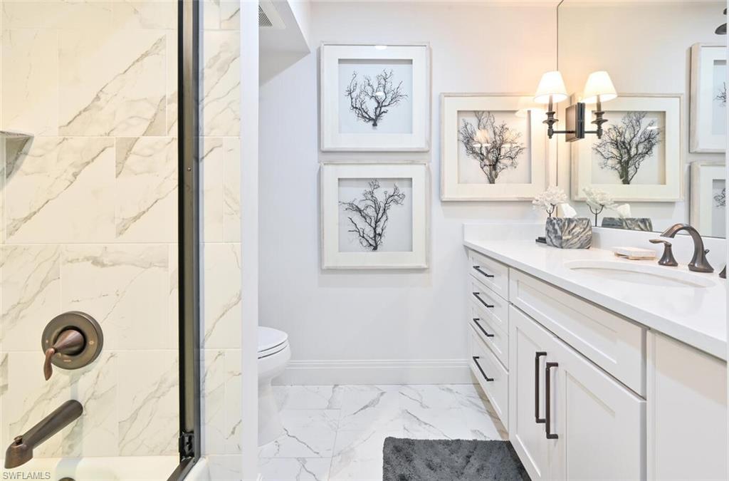 3105 Riviera Drive, Unit A201 Naples, FL 34103 - Photo 27 of 30 a bathroom with a sink a mirror and a shower
