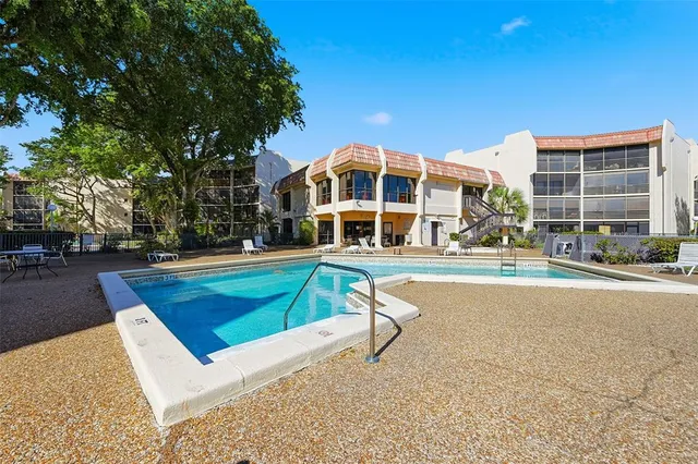 a view of a swimming pool with a lawn chairs under an umbrella