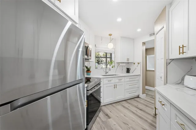 a kitchen with white cabinets and stainless steel appliances