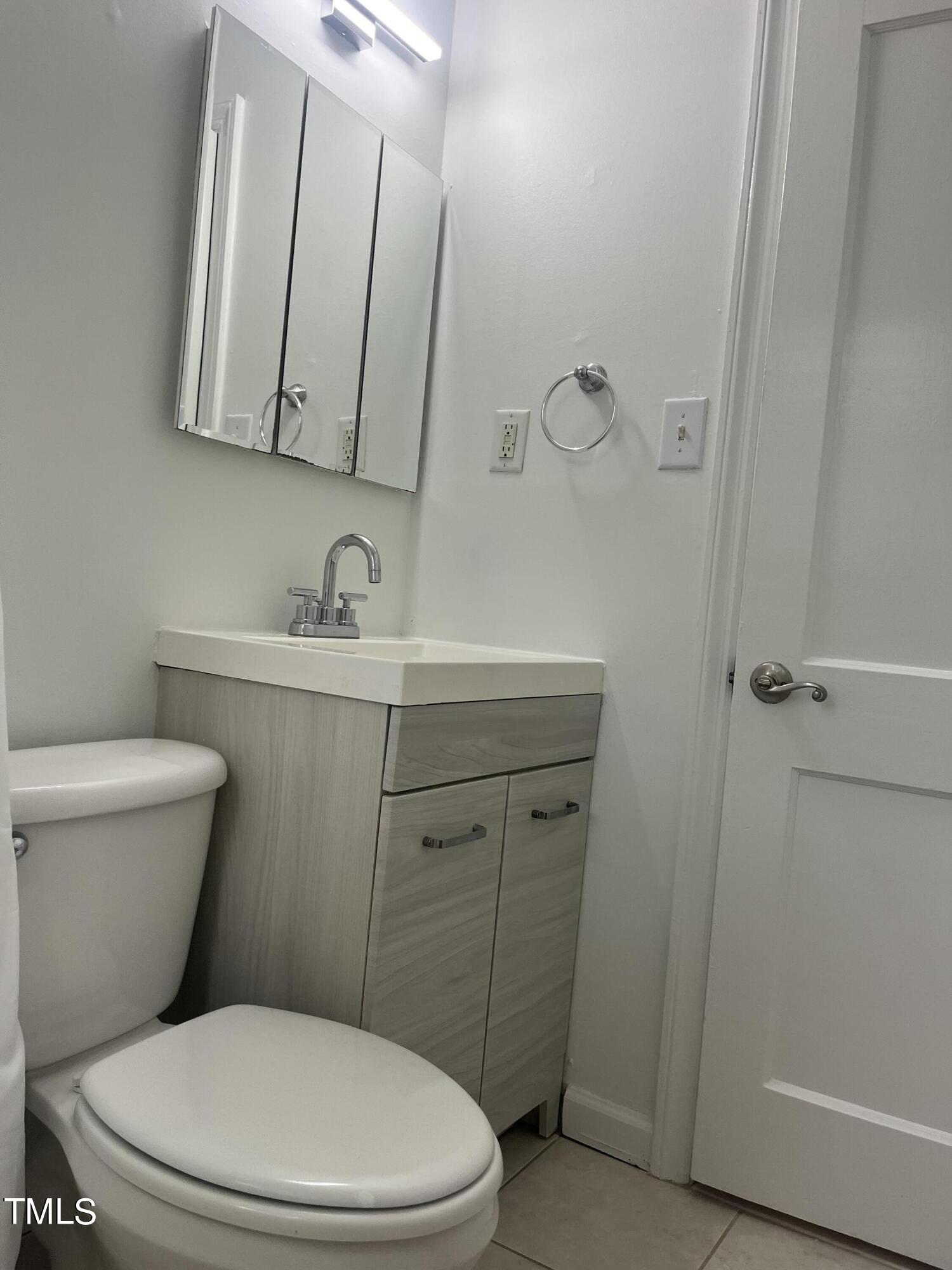 2626 McNeil Street Raleigh, NC 27608 - Photo 10 of 15 a bathroom with a toilet a sink a mirror and vanity