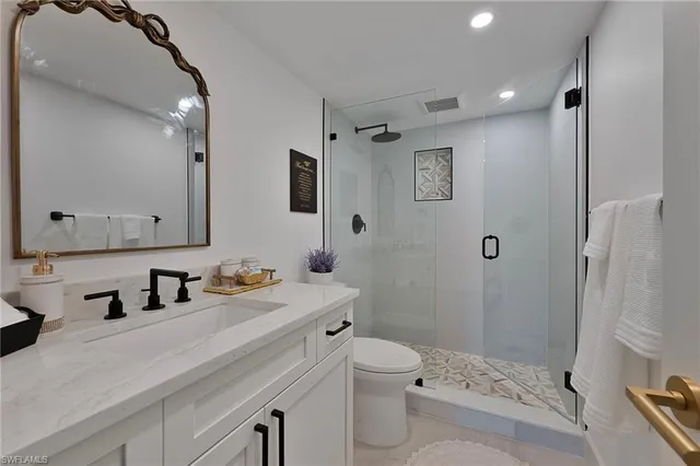 a bathroom with a sink a toilet a mirror and shower