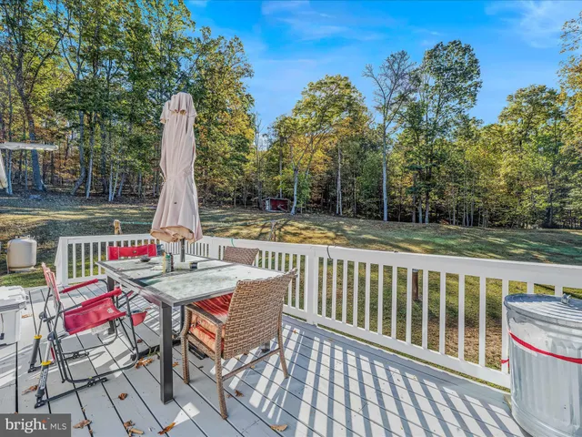 a view of a wooden house with large trees and playing area
