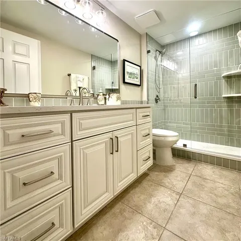 a spacious bathroom with a shower a sink a toilet and a mirror