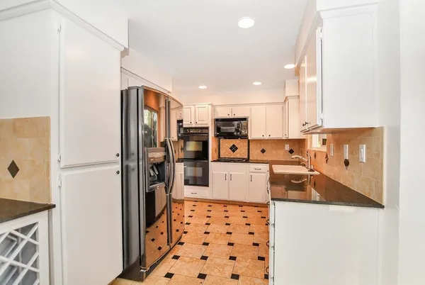 a kitchen with stainless steel appliances granite countertop a refrigerator and a stove top oven