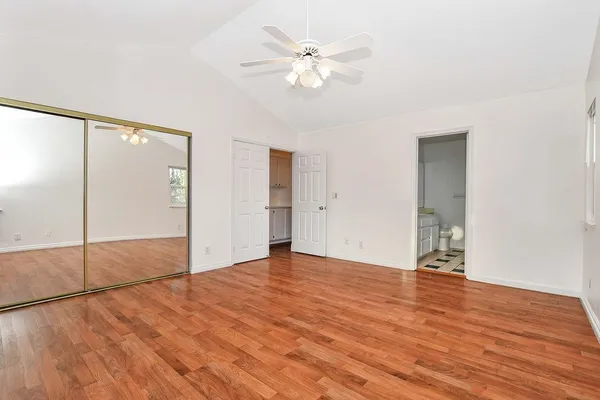 an empty room with wooden floor and fan chandelier