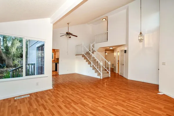 a view of empty room with wooden floor and fan