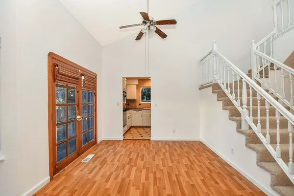 a view of empty room with wooden floor and fan