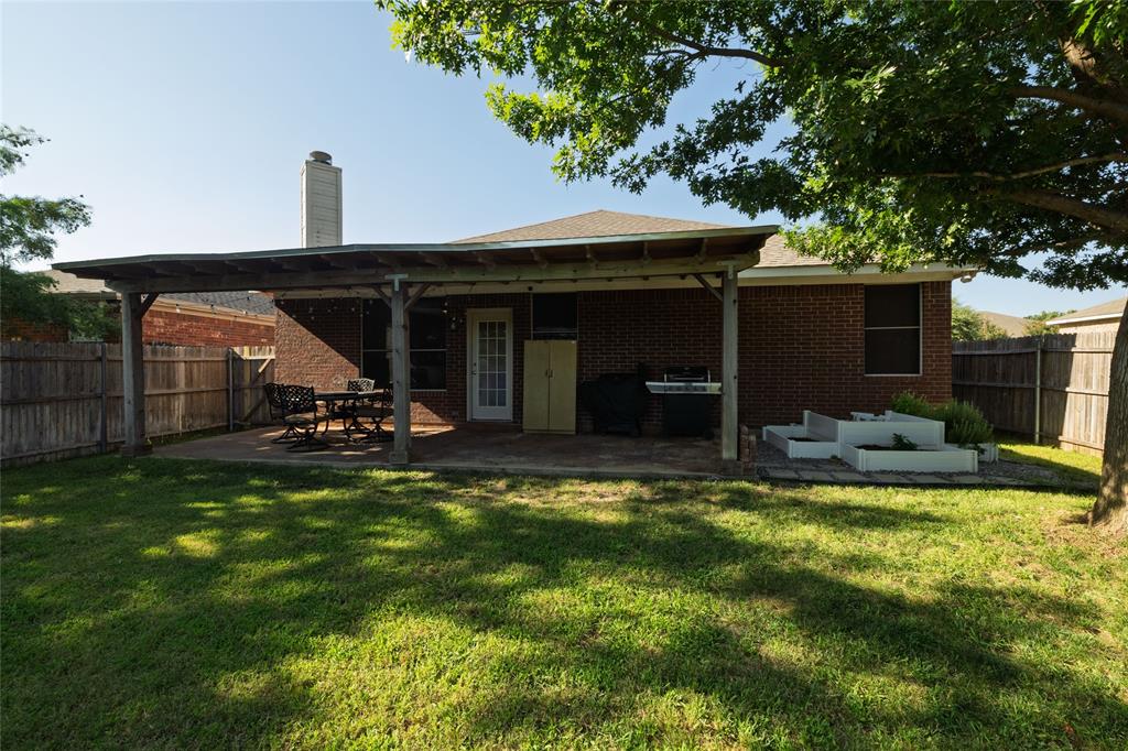 4025 Chisos Rim Trail Fort Worth, TX 76244 - Photo 38 of 40 Expansive backyard featuring a covered patio, brick exterior, wood privacy fencing, and raised garden beds