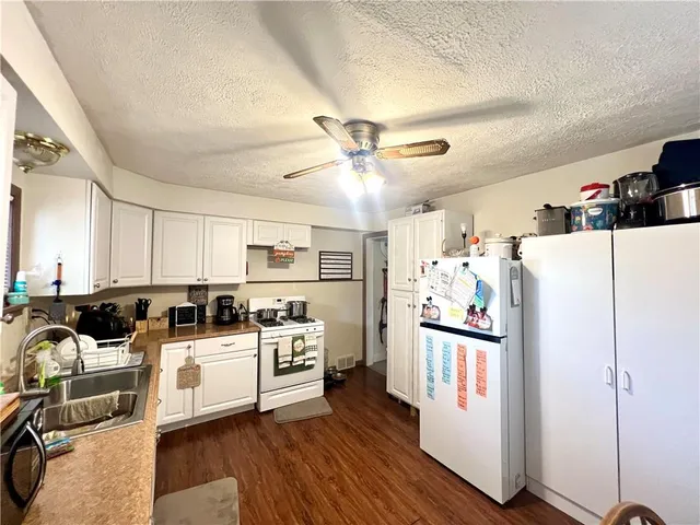 a kitchen with a refrigerator a stove top oven a sink and cabinets