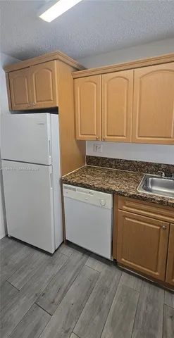 a kitchen with granite countertop cabinets stainless steel appliances and wooden floor