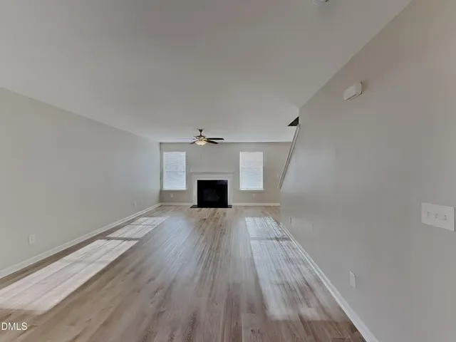a view of empty room with wooden floor and fireplace