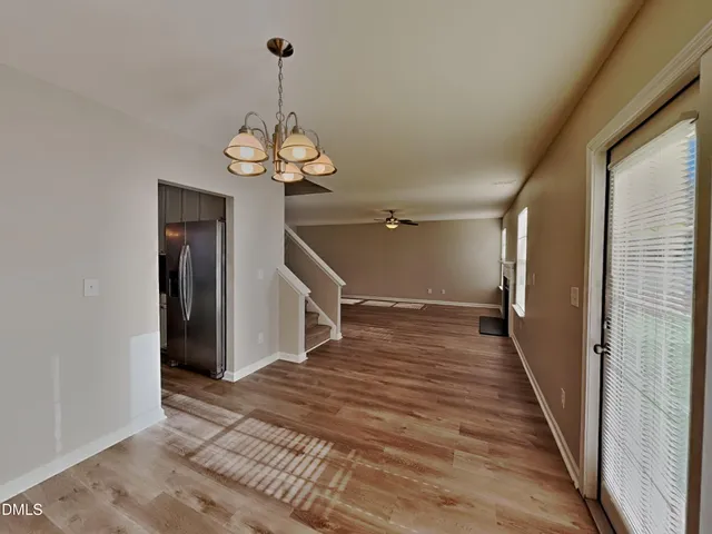 a view of a hallway with wooden floor and a chandelier