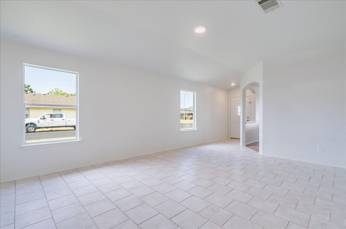 100 Easy Street Hutto, TX 78634 - Photo 4 of 36 A spacious, naturally illuminated room features light-toned tiled flooring and an inviting arched doorway.