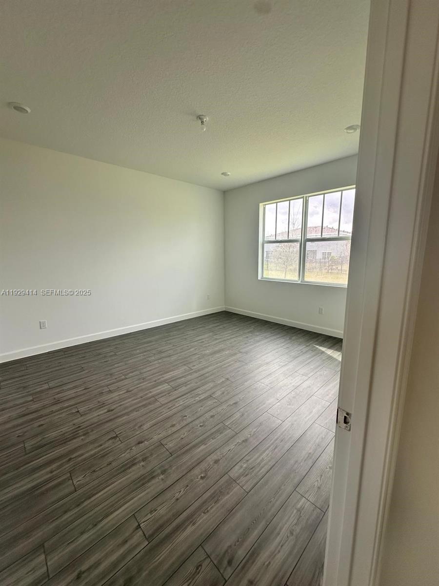 1443 Tangled Orchard Trace, Unit 1443 Loxahatchee, FL 33470 - Photo 16 of 33 an empty room with wooden floor and windows