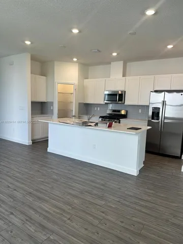 a large kitchen with stainless steel appliances a large counter top a stove and a refrigerator