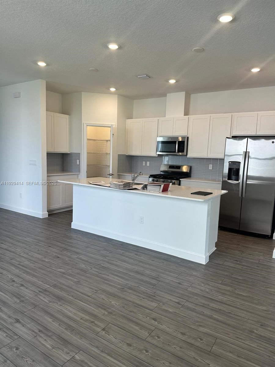 1443 Tangled Orchard Trace, Unit 1443 Loxahatchee, FL 33470 - Photo 6 of 33 a large kitchen with stainless steel appliances a large counter top a stove and a refrigerator