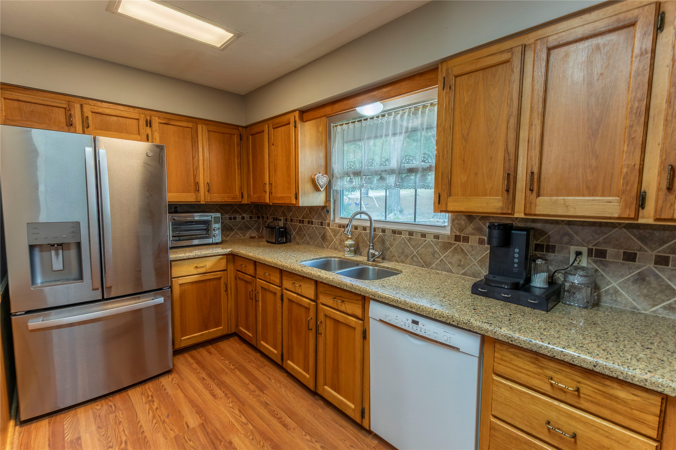 636 Deer Run Road Bellville, TX 77418 - Photo 4 of 23 a kitchen with stainless steel appliances granite countertop a refrigerator a sink dishwasher and wooden cabinets with wooden floor