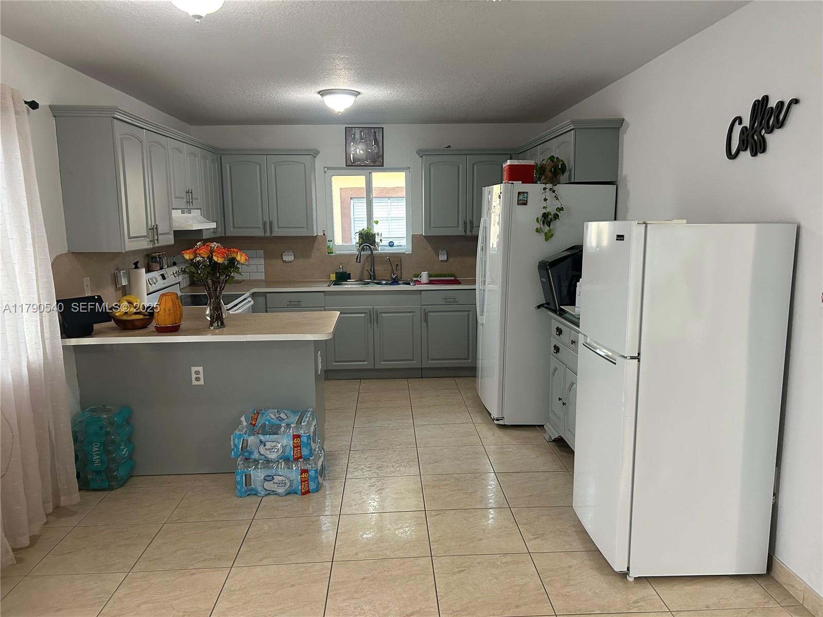 1446 Northwest 61st Street Miami, FL 33142 - Photo 30 of 54 a kitchen with a refrigerator and cabinets