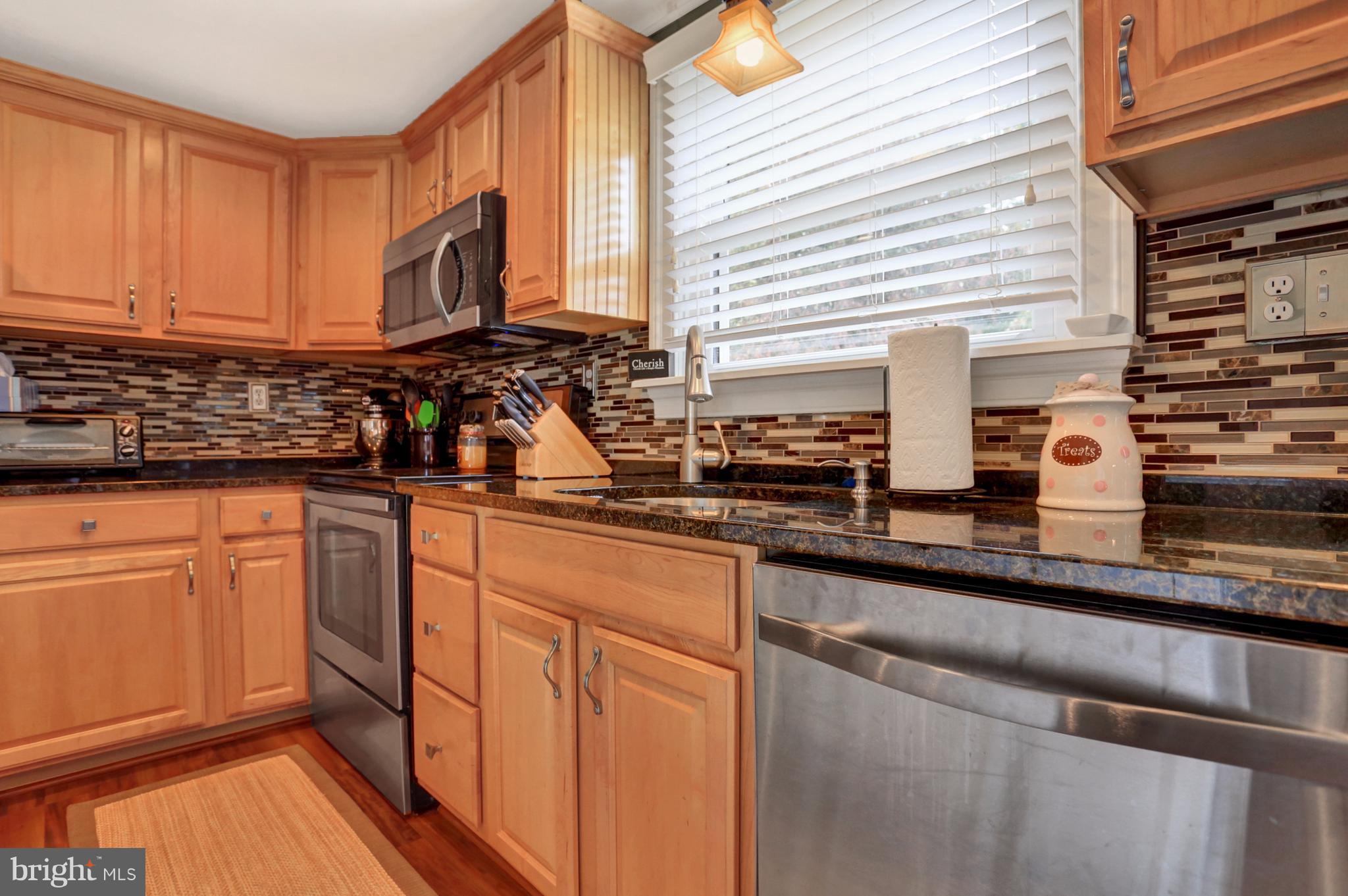 4629 Water Tank Road Manchester, MD 21102 - Photo 5 of 28 a kitchen with stainless steel appliances granite countertop a sink a stove and white cabinets with wooden floor