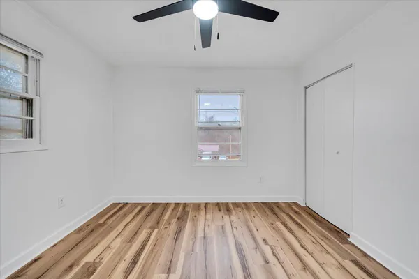 an empty room with a hardwood and ceiling fan