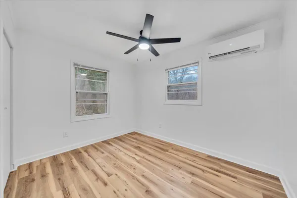 a view of empty room with wooden floor and fan