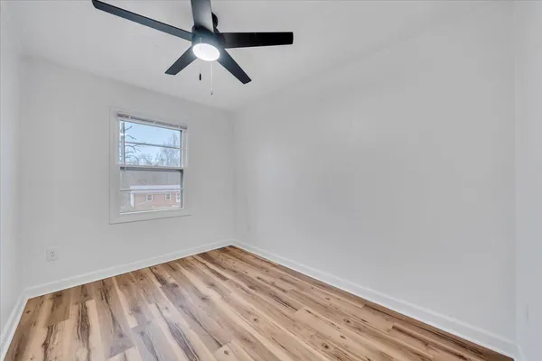 an empty room with a window and a ceiling fan