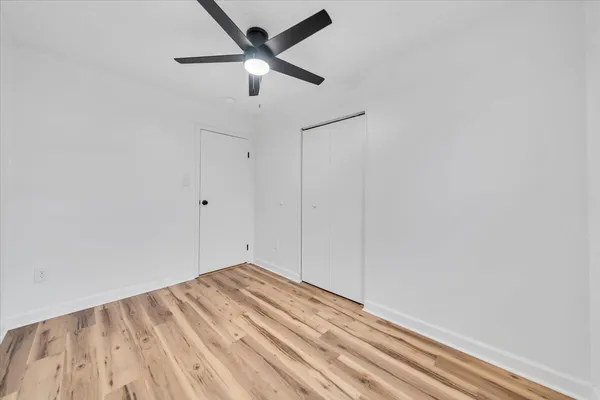 an empty room with a ceiling fan and wooden floor
