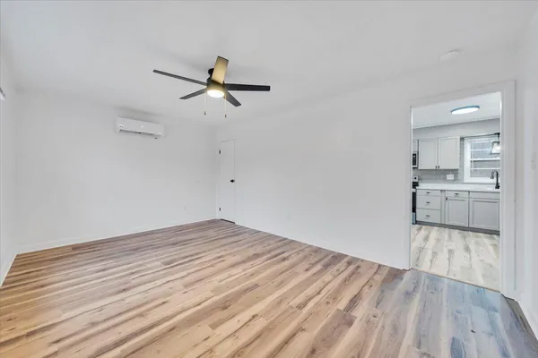 a view of kitchen and empty room with wooden floor