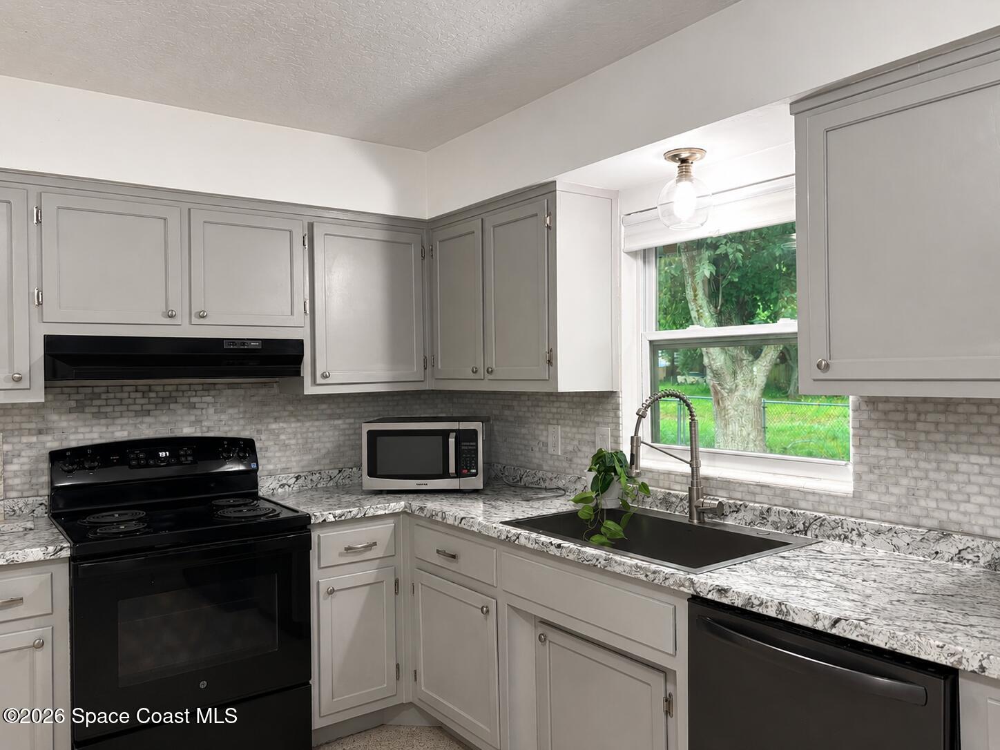 987 Kings Post Road Rockledge, FL 32955 - Photo 29 of 30 a kitchen with granite countertop a sink cabinets stainless steel appliances and a window