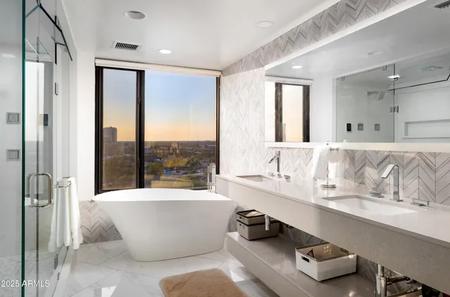 a large tub sitting next to a bathroom sink and a window