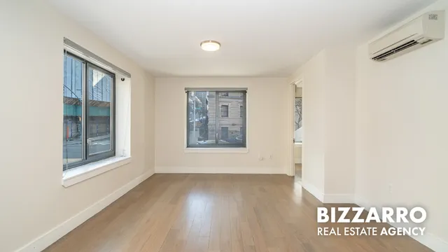 a view of an empty room with a window and wooden floor