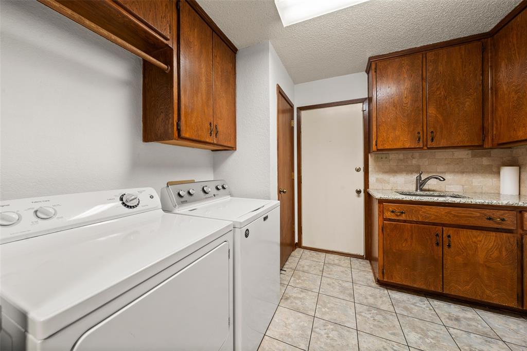 4121 Tokio Road West, TX 76691 - Photo 11 of 21 Laundry area featuring a textured ceiling, cabinet space, separate washer and dryer, and light tile patterned flooring