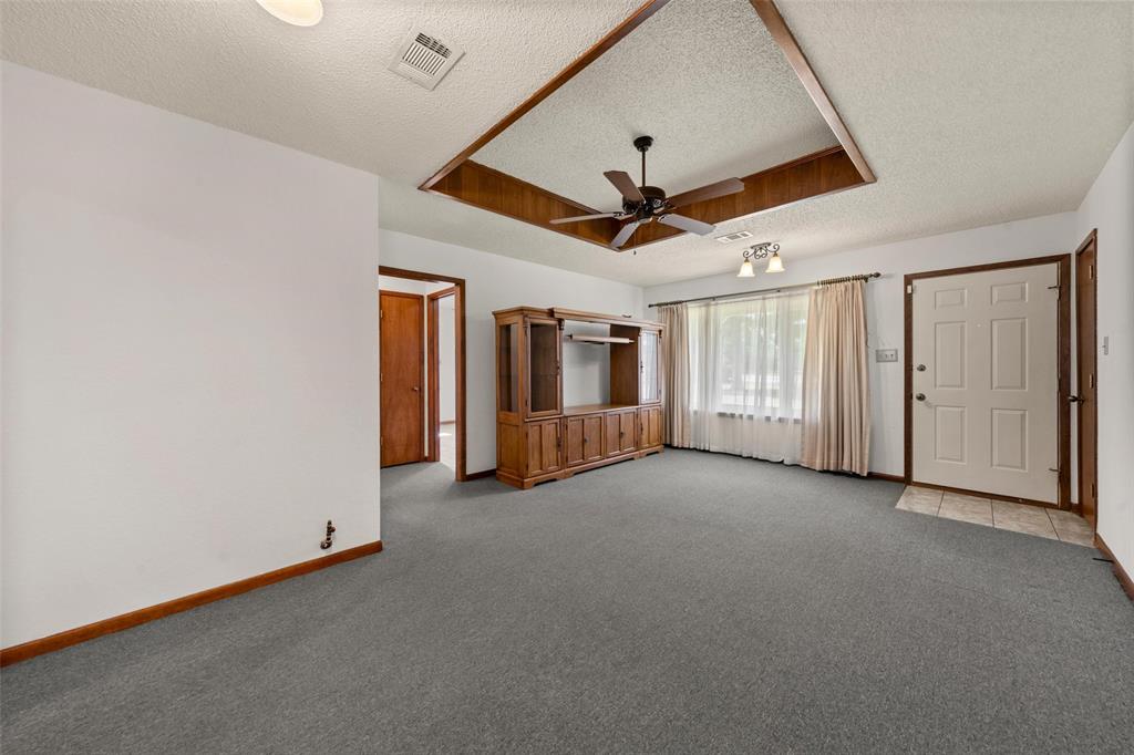 4121 Tokio Road West, TX 76691 - Photo 5 of 21 Unfurnished living room with a raised ceiling, a textured ceiling, carpet, and a ceiling fan