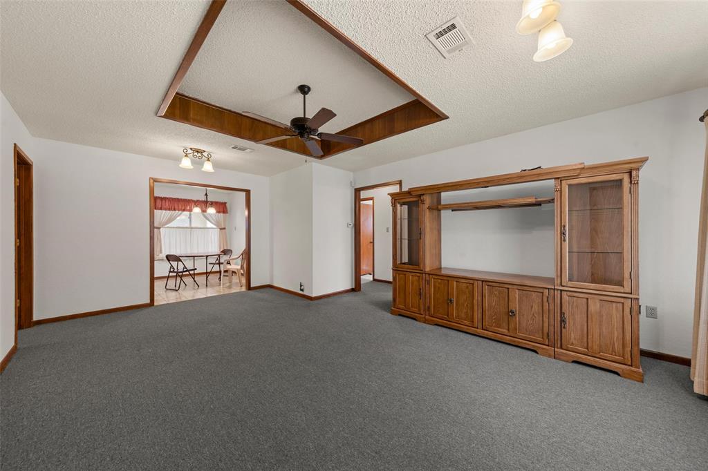 4121 Tokio Road West, TX 76691 - Photo 6 of 21 Empty room with a textured ceiling, a tray ceiling, light carpet, a ceiling fan, and a chandelier
