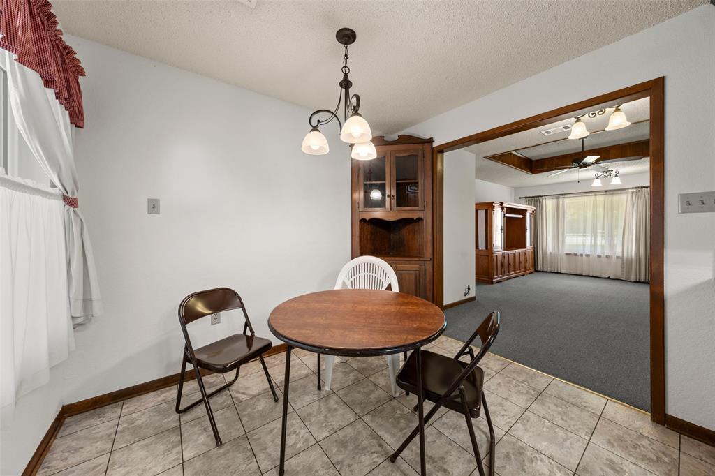 4121 Tokio Road West, TX 76691 - Photo 7 of 21 Dining area featuring a textured ceiling, light carpet, a raised ceiling, a chandelier, and light tile patterned flooring