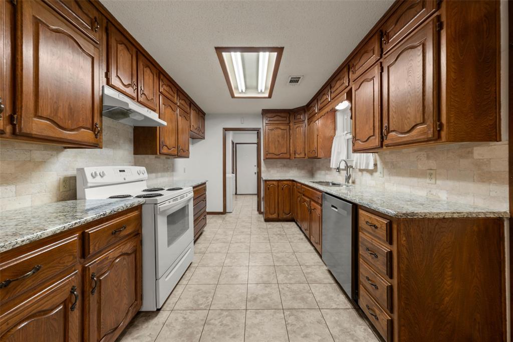 4121 Tokio Road West, TX 76691 - Photo 8 of 21 Kitchen with light stone countertops, white range with electric cooktop, tasteful backsplash, light tile patterned floors, and stainless steel dishwasher