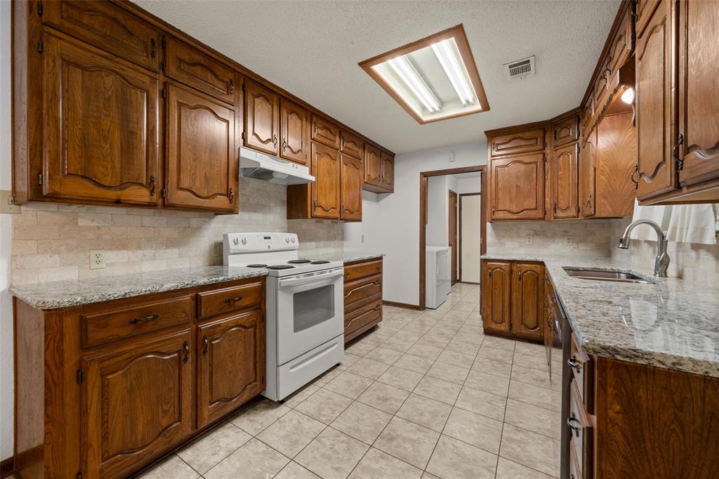 4121 Tokio Road West, TX 76691 - Photo 9 of 21 Kitchen with tasteful backsplash, light stone counters, white electric stove, and brown cabinetry