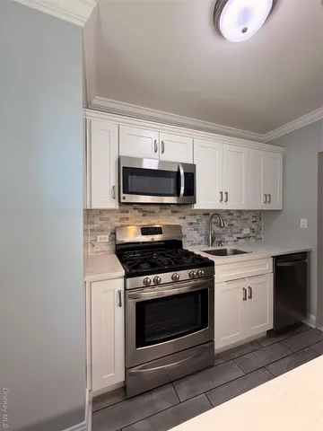 a kitchen with white cabinets and stainless steel appliances