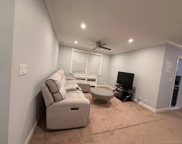 a living room with furniture a flat screen tv and a window
