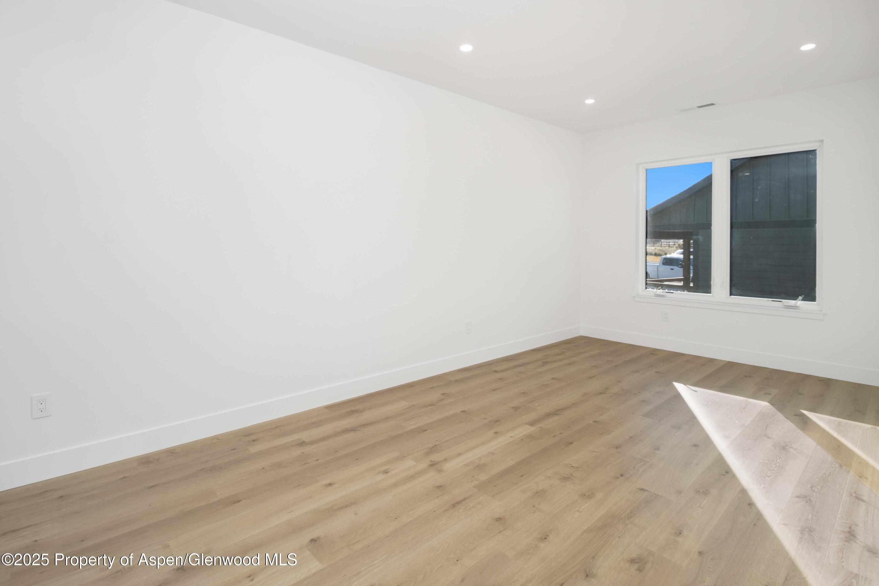 1411 Rifle Heights Drive Rifle, CO 81650 - Photo 16 of 31 an empty room with wooden floor and windows
