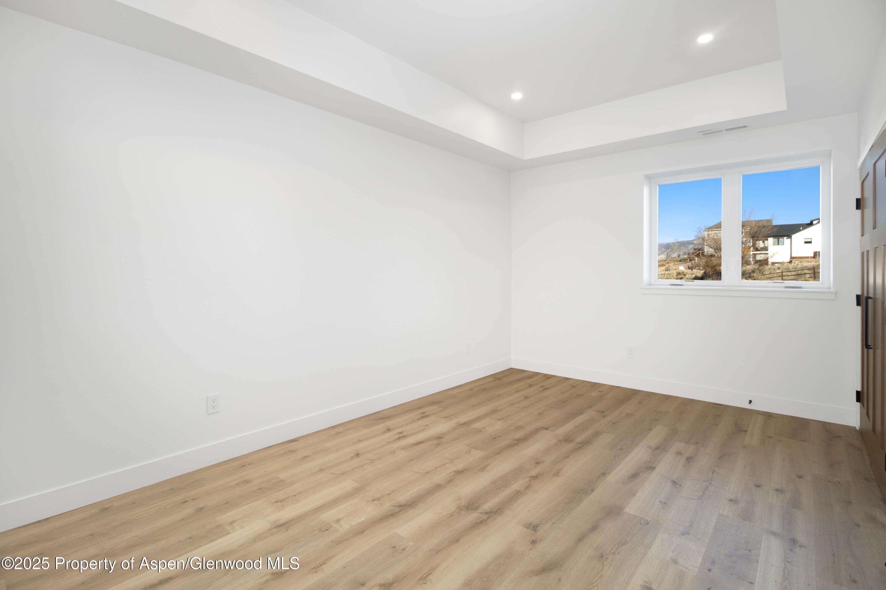 1411 Rifle Heights Drive Rifle, CO 81650 - Photo 24 of 31 an empty room with wooden floor and windows