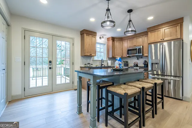 a kitchen with kitchen island granite countertop wooden floors and refrigerator