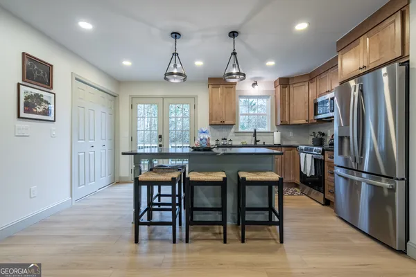 a kitchen with stainless steel appliances granite countertop a refrigerator a stove a sink dishwasher a dining table and chairs with wooden floor