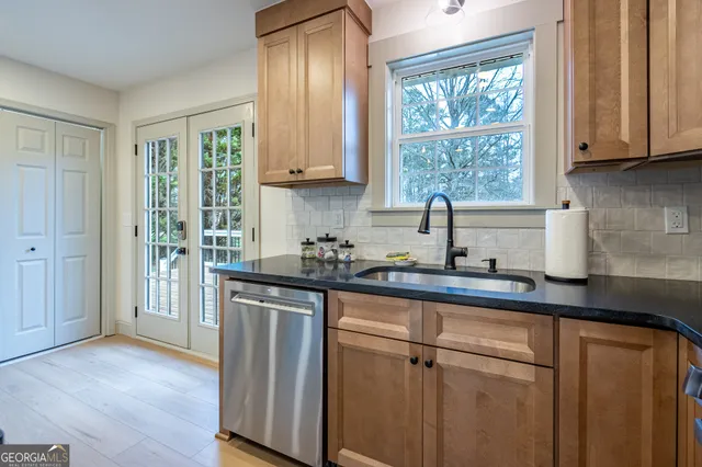 a kitchen with stainless steel appliances granite countertop white cabinets a sink and a window