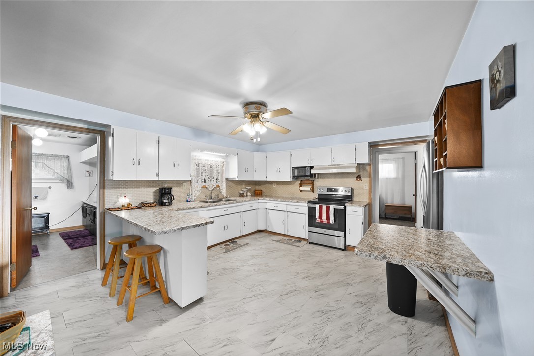 6677 Fee Road Rome, OH 44085 - Photo 11 of 39 Kitchen featuring electric stove, a kitchen bar, sink, ceiling fan, and white cabinets