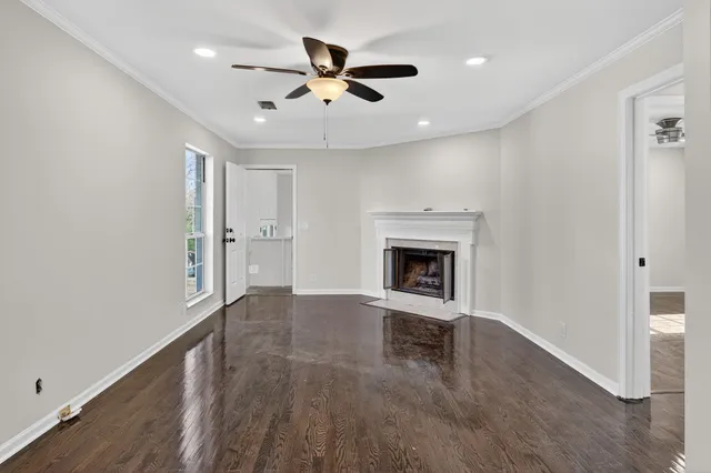 a view of an empty room with a fireplace and a chandelier fan