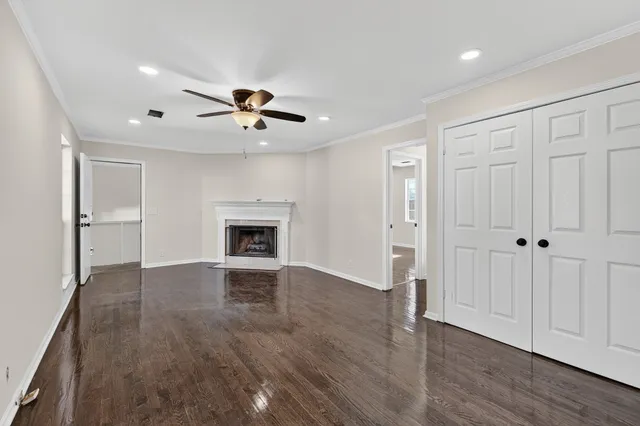 a view of an empty room with wooden floor fireplace and a window