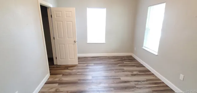 an empty room with wooden floor and window