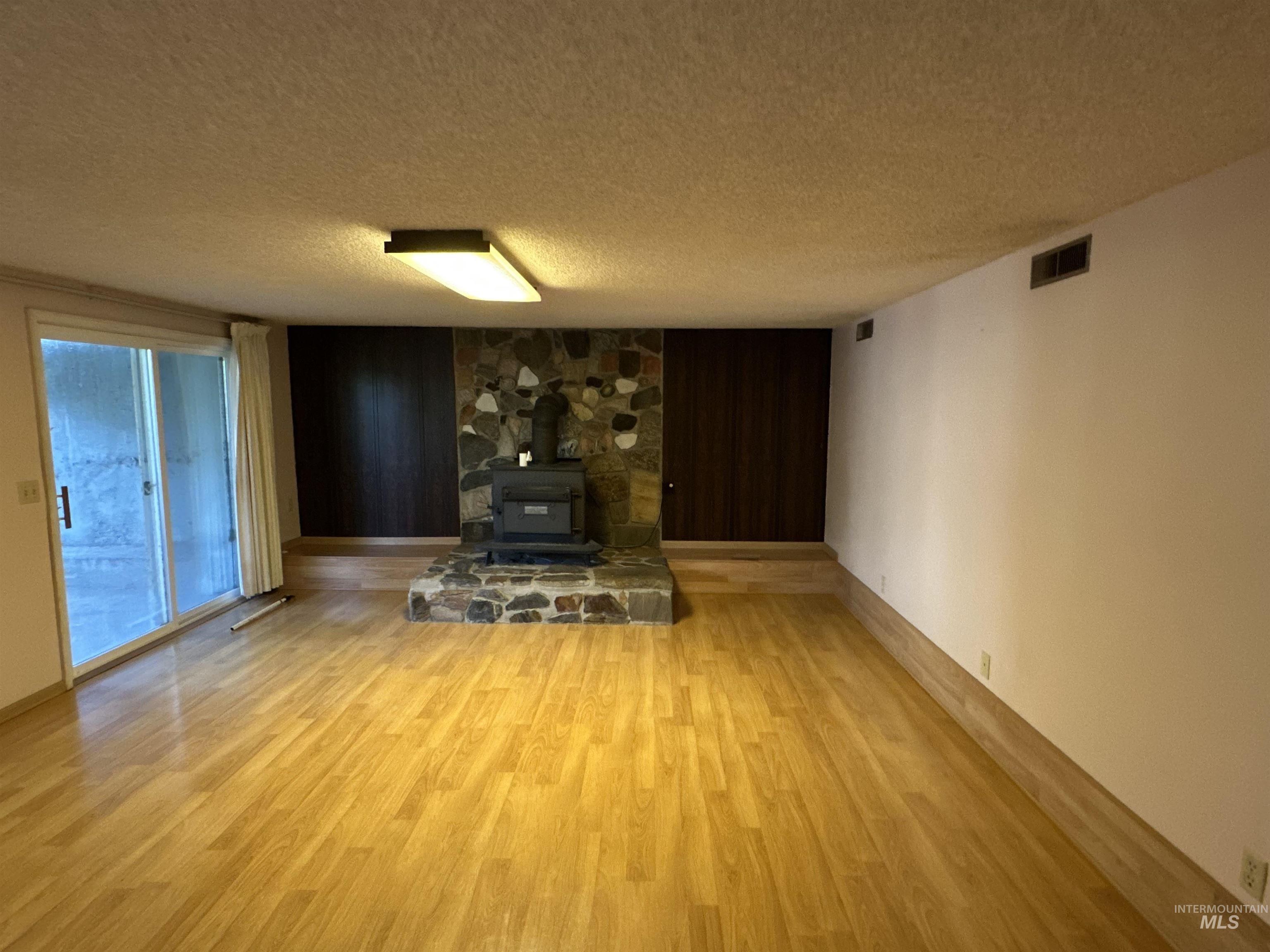 1620 6th Avenue Clarkston, WA 99403 - Photo 14 of 19 Spacious interior featuring wood-finish flooring and a stone-clad fireplace with wood-burning stove